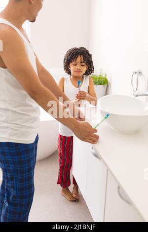 Hispanic boy looking at brush while standing by father in bathroom at home Stock Photo
