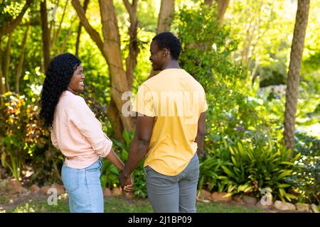 Smiling african american mid adult couple looking at each other while holding hands in backyard Stock Photo