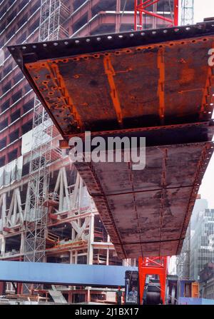 Construction site. Large steel plank hoisted by crane onto multi story building under new construction. Business financial and industrial growth Stock Photo