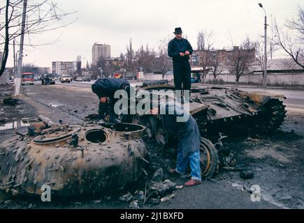 First Chechen War, November 1994.  Civilians look at a destroyed Russian T-72 tank on the street in Grozny, Chechnya. Stock Photo