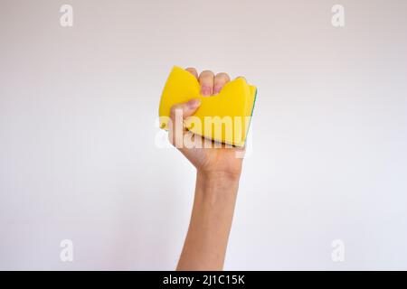 Hand holding a yellow sponge isolated on white background. Stock Photo