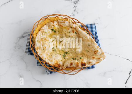 Crispy garlic naan in a basket isolated on napkin side view on grey background famous indian and pakistani food Stock Photo