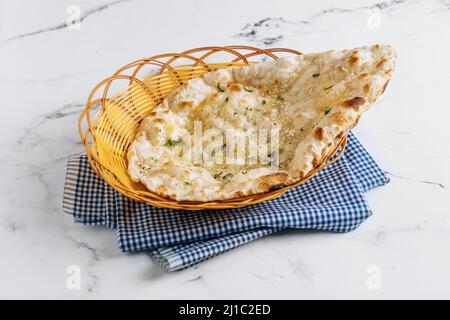 Crispy garlic naan in a basket isolated on napkin side view on grey background famous indian and pakistani food Stock Photo