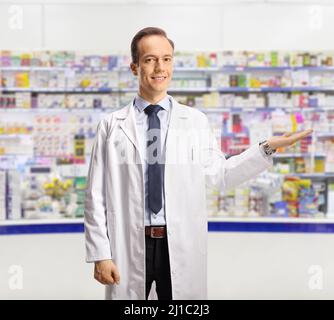 Male pharmacist showing with hand inside a pharmacy Stock Photo