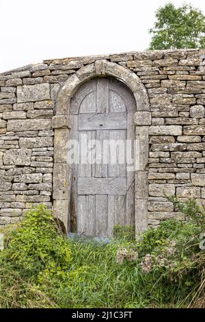 A rather curious door in a dry stone wall leading into a perfectly ordinary field near the Cotswold village of Dowdeswell, Gloucestershire, England UK Stock Photo