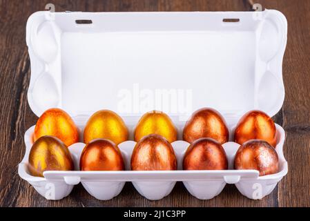 Plastic packaging with Easter eggs dyed to look like non-ferrous metals. Packaging with eggs on a wooden background. Stock Photo