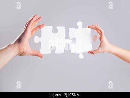 Mens and childs hands connecting puzzles. Hands connecting puzzle. Puzzles. Hand of the child and hand of mother fold puzzle, closeup. Hands hold Stock Photo
