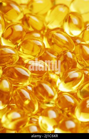 The texture of the capsules in the shell with liquid vitamin D3 in full screen. Gold capsules with a dietary supplement for joints teeth and bones. Stock Photo