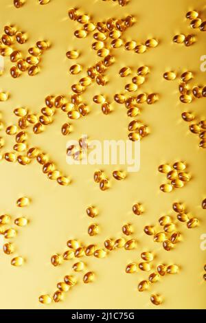 The texture of the capsules in the shell with liquid vitamin D3 in full screen. Gold capsules with a dietary supplement for joints teeth and bones. Stock Photo