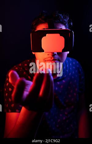 Young latin man using Virtual Reality VR Headset 3D Glasses. Dark backdrop. Low key. Stock Photo