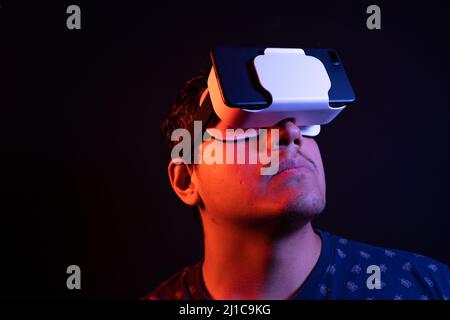 Young latin man using Virtual Reality VR Headset 3D Glasses. Studio dark backdrop. Low key.  Stock Photo
