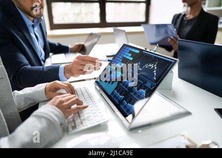 Side View Of Businesspeople Examining Graph On Computer At Workplace Stock Photo