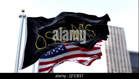 Hollywood, CA, USA, March 2022: the flag with the Academy Awards logo waving with the American flag blurred in the background. The Academy Award, aka Stock Photo