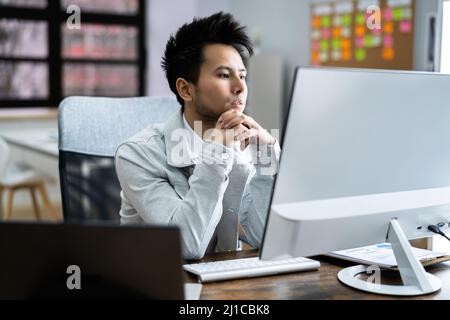 Pondering Thinking Businessman Using Office Computer. Contemplative Man Stock Photo