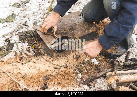Man cutting wood using stationary circular saw outdoors in winter for kindling close-up Stock Photo