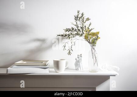 Dry eucalyptus branches in a ceramic vase, a modern fox figurine, photo frames, a notebook and a crumpled sheet of paper on a white background. Scandi Stock Photo