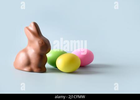 Easter chocolate bunny and colorful eggs on blue background with copy space. Happy Easter greeting card. Banner. Stock Photo