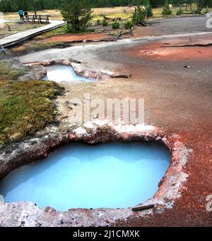 Blue pool is part of the Artists Paint Pots in Yellowstone National Park.  Visitors walk on boardwalk to see the pots. Stock Photo