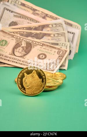 A pile of dollars and a few dogecoin on a green table. Photograph in vertical format. Copy space. Stock Photo