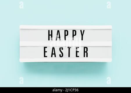 HAPPY EASTER written in light box on a light blue background. Top view, copy space Stock Photo