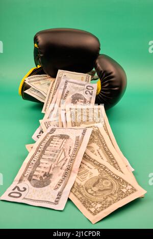 Vertical view of some boxing gloves with a lot of dollars on a green background Stock Photo