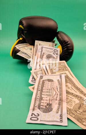 Vertical view of some boxing gloves with a lot of dollars on a green background Stock Photo