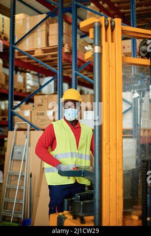 African worker man pulling a pallet truck at warehouse store - Industry during coronavirus outbreak concept - Focus on face Stock Photo