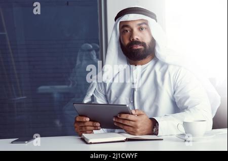Partnering with technology to achieve success. Cropped portrait of a young businessman dressed in Islamic traditional clothing using a digital tablet Stock Photo