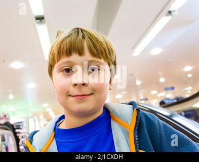 child on moving staircase looks self confident and smiles Stock Photo