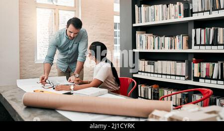 Technology is the cherry on top of their expertise. Cropped shot of two aspiring young architects using a digital tablet while working together in a Stock Photo