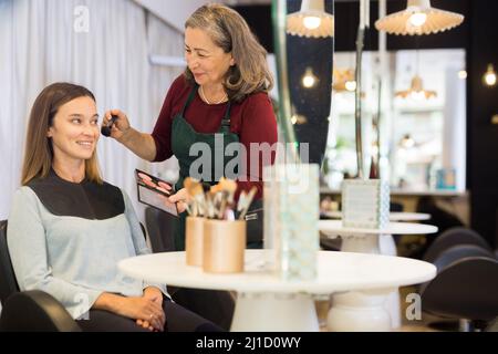 Elderly woman makeup artist working in beauty studio with young female client Stock Photo