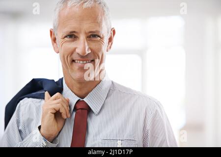 Youve picked the right man for the job. Portrait of a mature businessman with his jacket over his shoulder standing in an office. Stock Photo