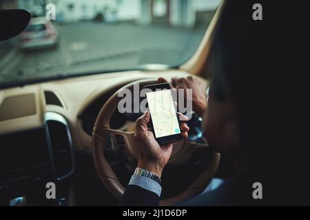 Getting there safely thanks to gps. Cropped shot of a businessman using his phones gps while driving a car. Stock Photo