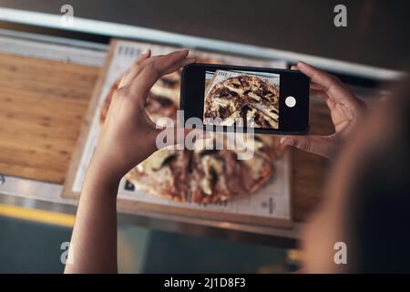 I have to put this on my blog. Cropped shot of an unrecognizable woman sitting alone and using her cellphone to photograph her pizza at a restaurant. Stock Photo