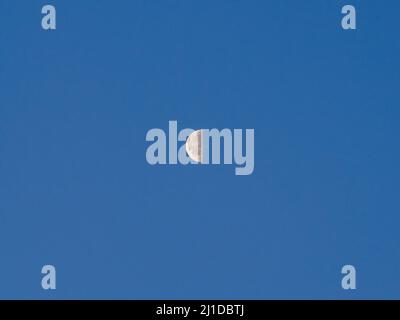 half face of the moon with clear blue sky Stock Photo