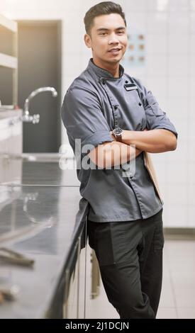 Proud of my kitchen. Cropped portrait of a young male chef standing with his arms folded in the kitchen. Stock Photo