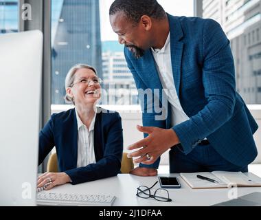 Youve got the best approach to problems. Shot of two businesspeople having a discussion in the office while using a computer. Stock Photo