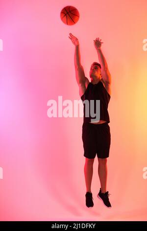Shoot your shot. Studio shot of a handsome young male basketball player taking a jump shot against a multi-coloured background. Stock Photo