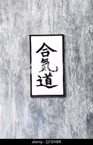 Calligraphy - Aikido symbol on wooden background.  Japanese aikidō (“way of harmonizing energy”) is a martial art and self-defense system. Stock Photo