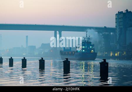 Kiel, Germany. 25th Mar, 2022. The coaster 'Helena VG' sails across the Kiel Canal towards the high bridge in Holtenau. The Annual Balance PK General Directorate the General Directorate of Waterways and Shipping gives the traffic figures for the year 2021 for the Kiel Canal. Credit: Axel Heimken/dpa/Alamy Live News Stock Photo