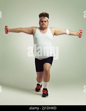 Lunges and more lunges. Shot of an overweight man doing lunges while holding up dumbbells. Stock Photo
