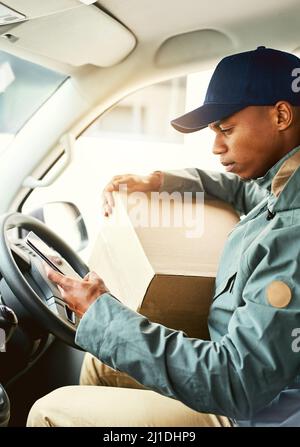 Finding the quickest route to his next delivery. Shot of a courier using a cellphone while sitting in a delivery van. Stock Photo