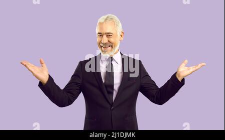 Happy senior man in suit spreads his arms welcoming and greeting you on pastel purple background. Stock Photo