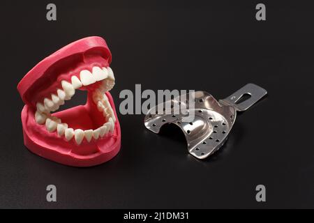 Stainless steel dental tols and layout of a human jaw on the black background. Stock Photo