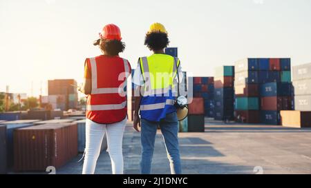 Woman foreman or engineer using binoculars and partner pointing at problem focus cargo container tank at the warehouse container logistic transportati Stock Photo
