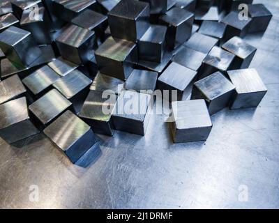 pile of small machined shiny steel cubes on metal surface Stock Photo