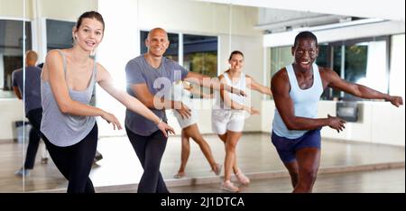 Cheerful people practicing vigorous lindy hop movements in dance class Stock Photo