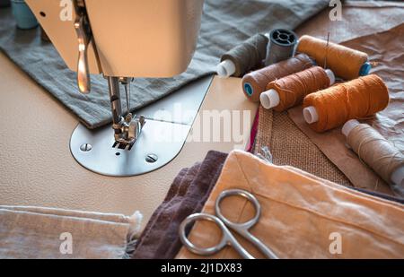 Sewing machine, thread, scissors and fabric close-up. Design workplace. Stock Photo