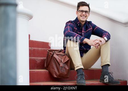 My friends should be here any minute. Portrait of a handsome young man sitting on some steps outside. Stock Photo