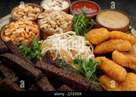 A variety of beer snacks, peanuts, nuggets, squid sauces croutons Stock Photo